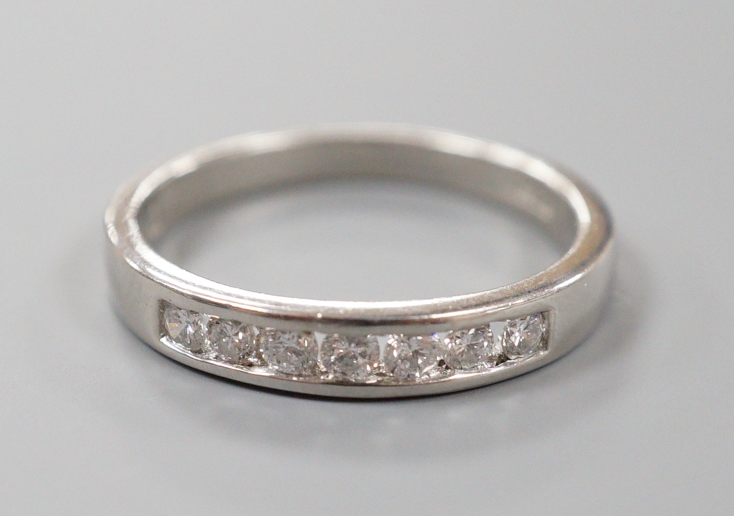 A modern platinum and channel set seven stone half hoop ring, size P, gross weight 5.1 grams